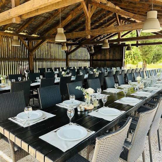 Natkrivena drvena terasa restorana sa dugim postavljenim stolovima